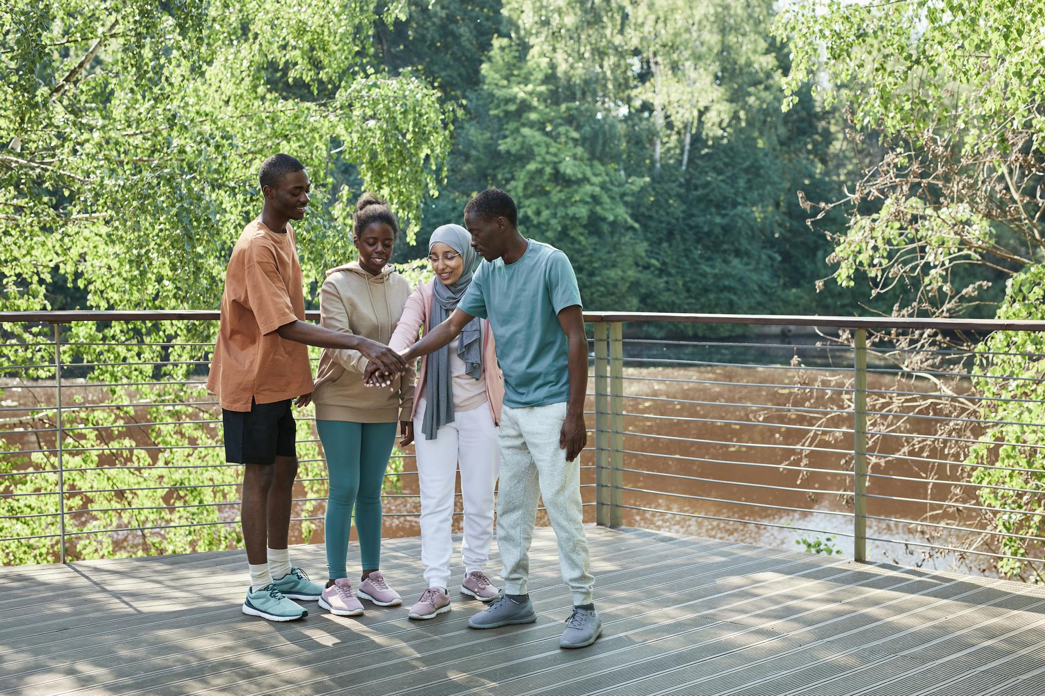 A diverse group of friends joining hands on a sunny day, symbolizing unity and teamwork.